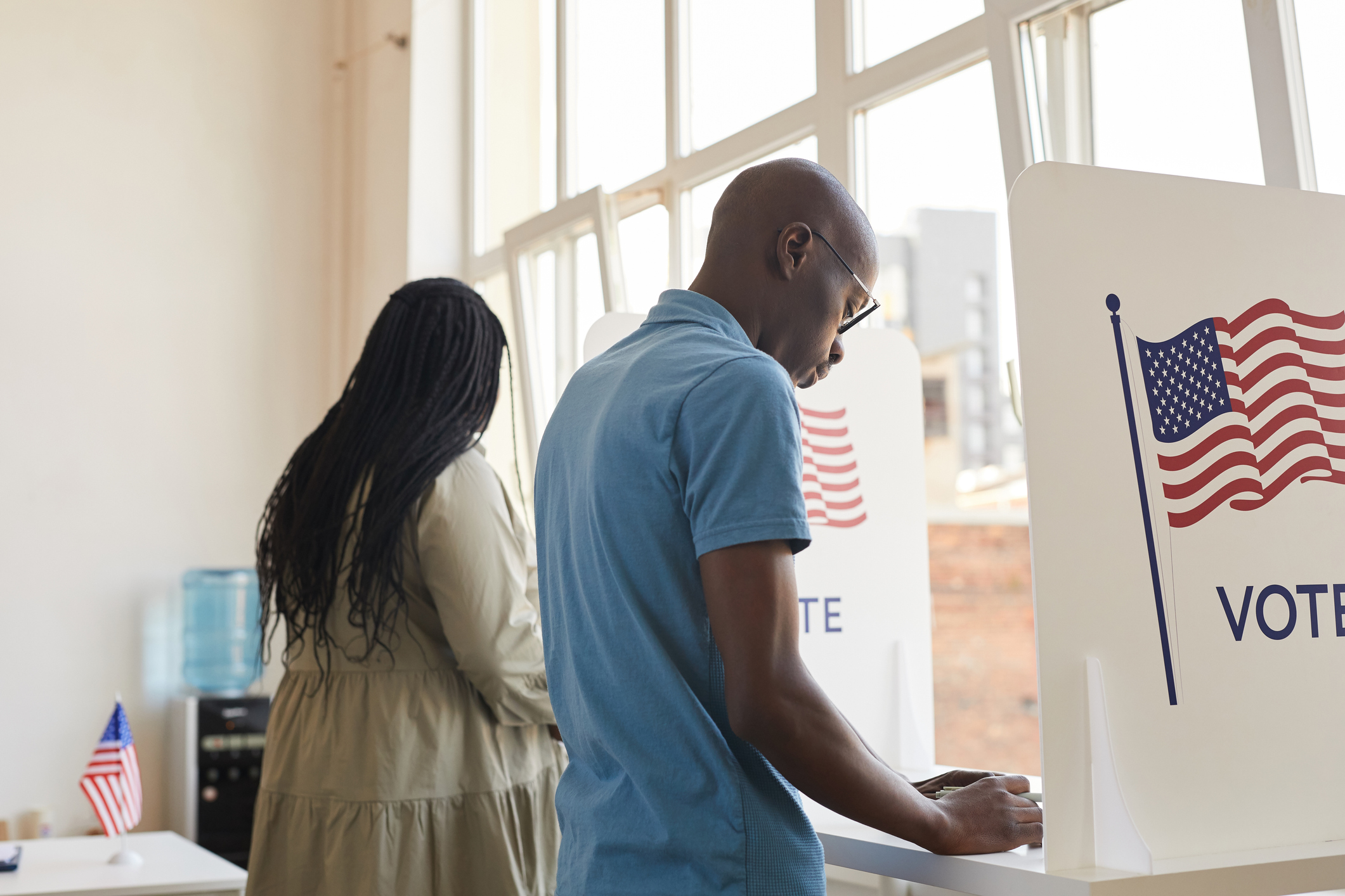 Two African American people in separate voting booths