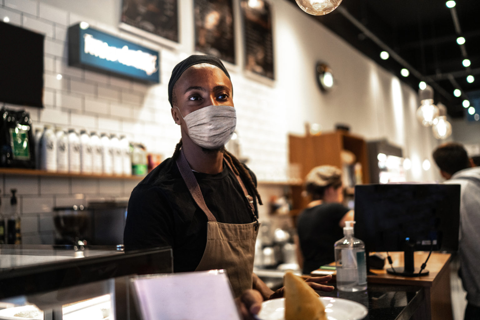 Young Black waiter with face mask working in coffee shop