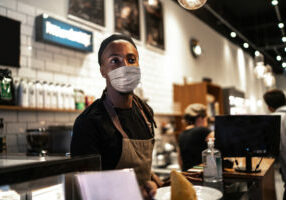 Young Black waiter with face mask working in coffee shop